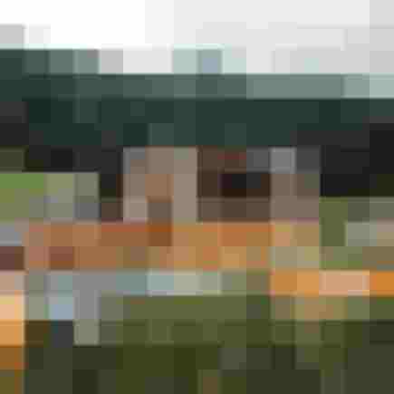 Beleuchtetes Berghotel mit Pool und umliegendem Wald aus der Luftaufnahme