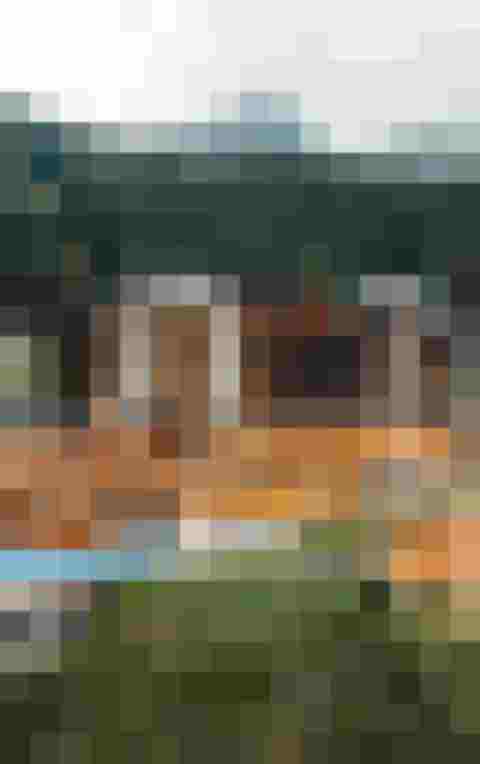 Beleuchtetes Berghotel mit Pool und umliegendem Wald aus der Luftaufnahme